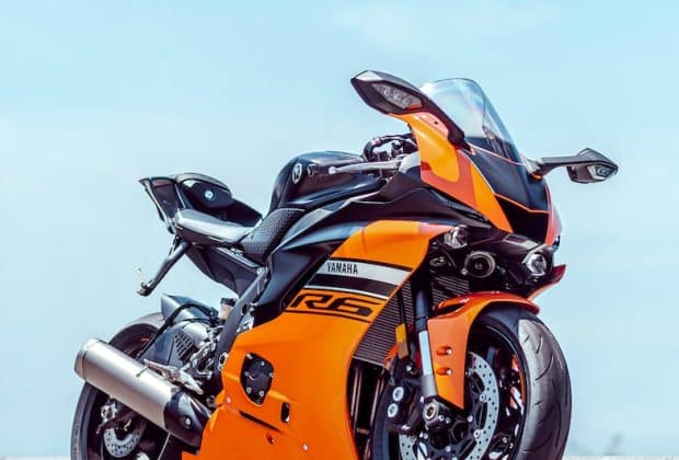 orange and black sports bike parked on gray concrete pavement during daytime