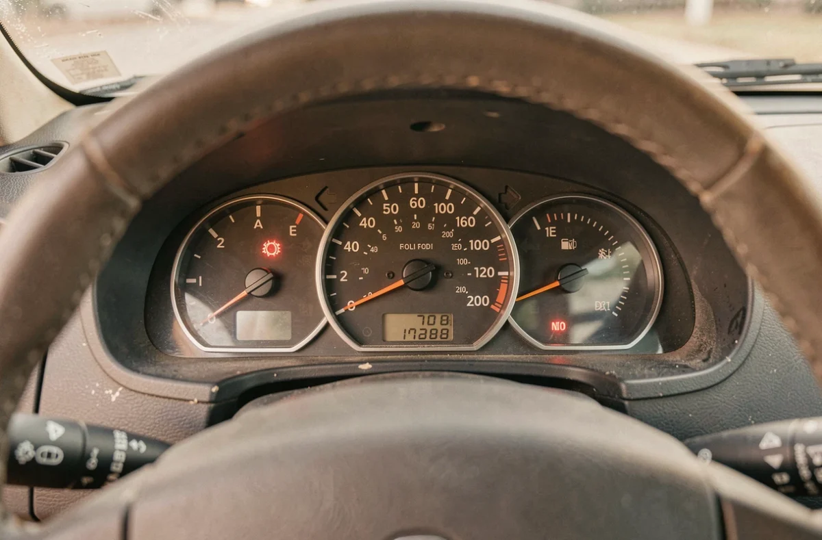 Gros plan sur le tableau de bord intérieur d'une Renault Clio II avec les cadrans et voyants d'avertissement visibles