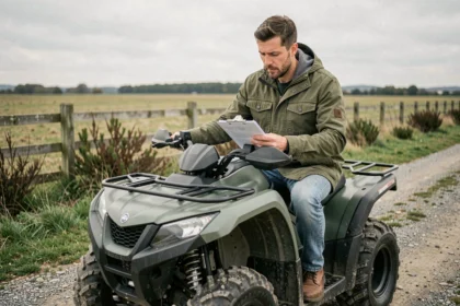 Homme assis sur un quad tout-terrain en campagne consultant des documents d'assurance