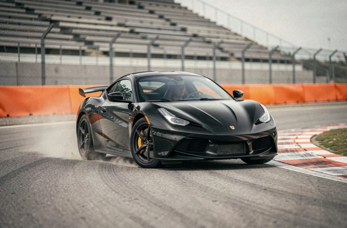 Voiture de sport en pleine trajectoire sur circuit automobile lors d'un stage de pilotage haute performance